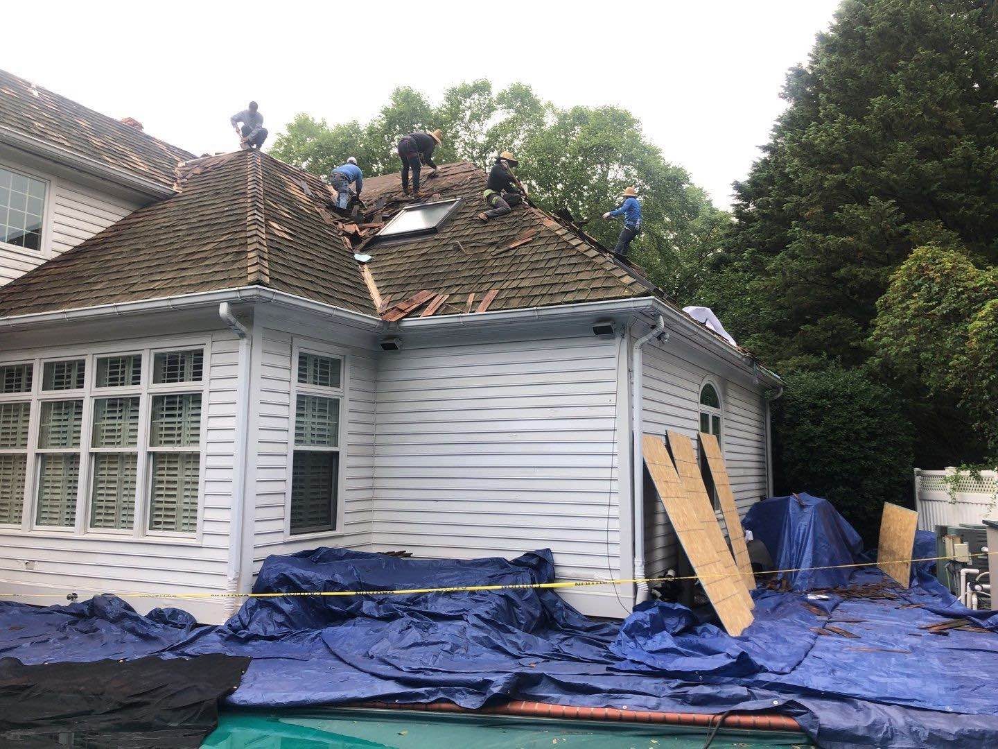 Blue emergency roof tarp secured over storm-damaged shingles on a St. Louis home at night