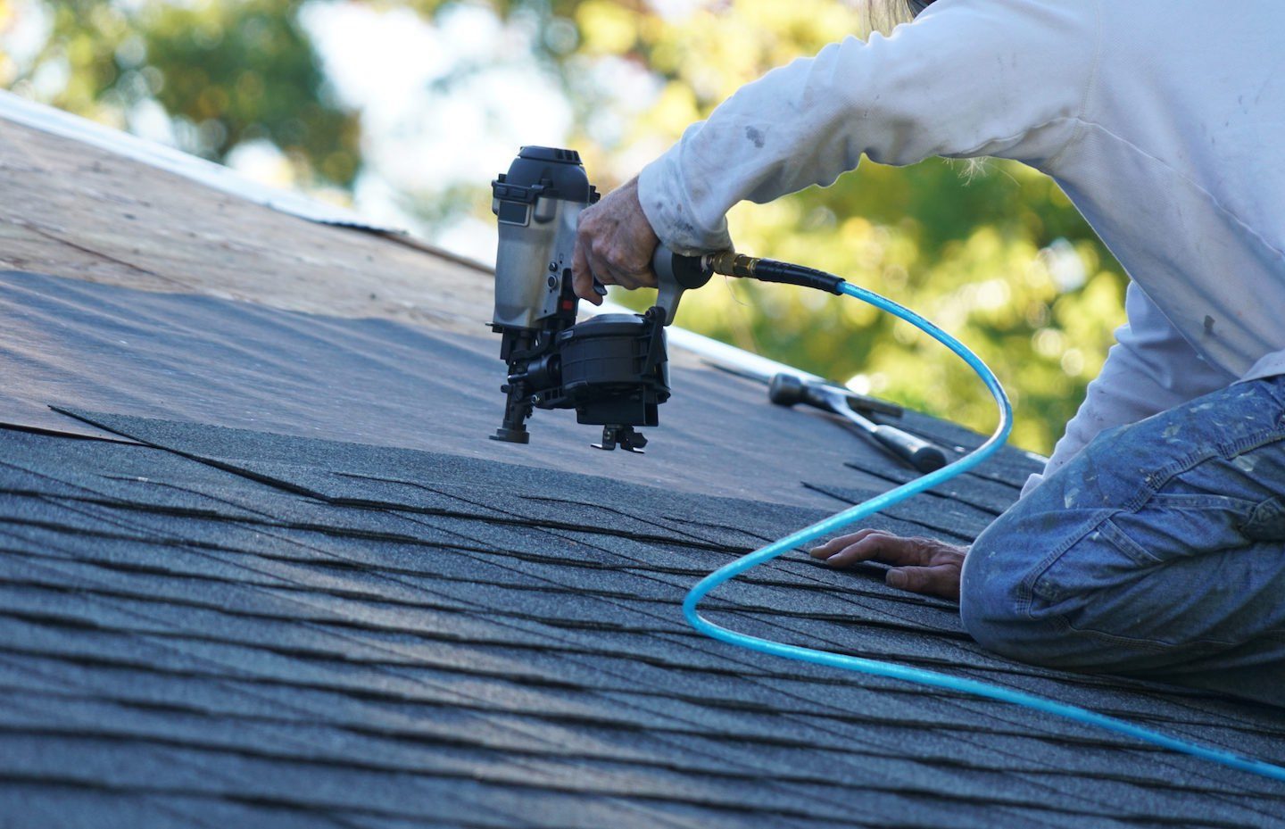 Close-up of damaged asphalt shingles and exposed flashing on a St. Louis roof before repair