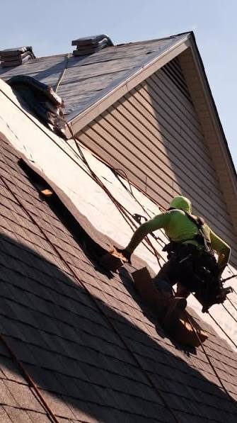 Roofer in a safety harness on a steep Ballwin MO roof during a roof replacement